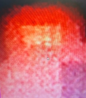 Close-up still from surveillance footage showing a bright red-orange glow against a deep red background