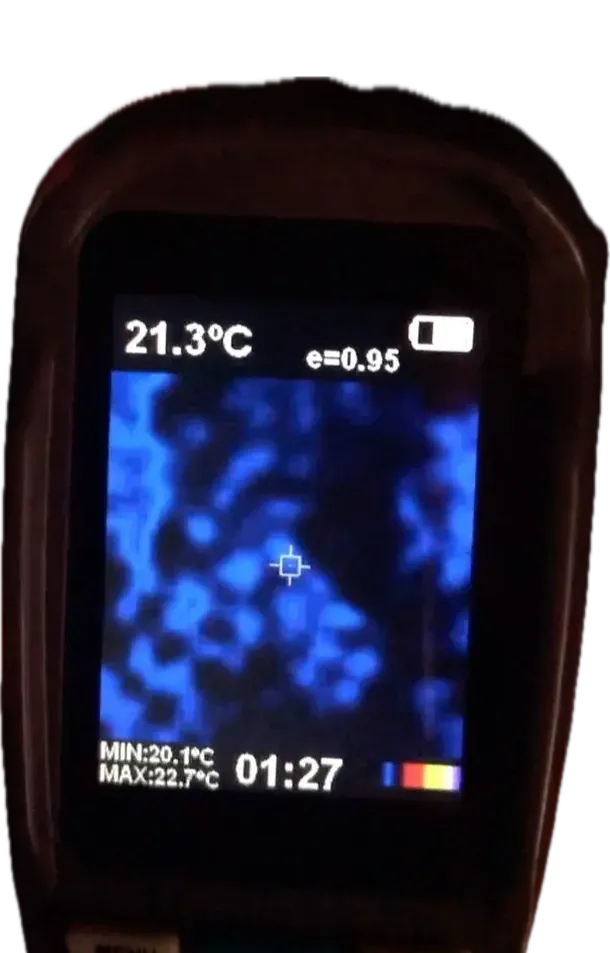 Photo of a handheld thermal imaging camera device displaying a blue heat map reading of 21.3 degrees Celsius